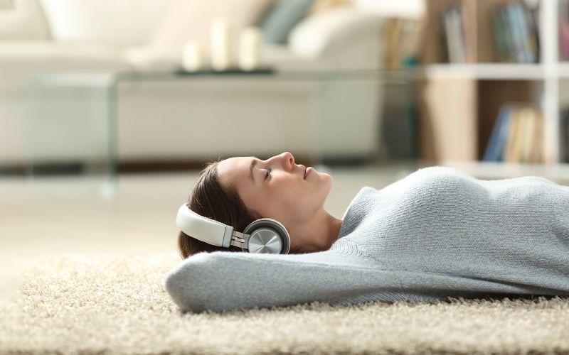 Mujer tumbada sobre una alfombra escuchando musica